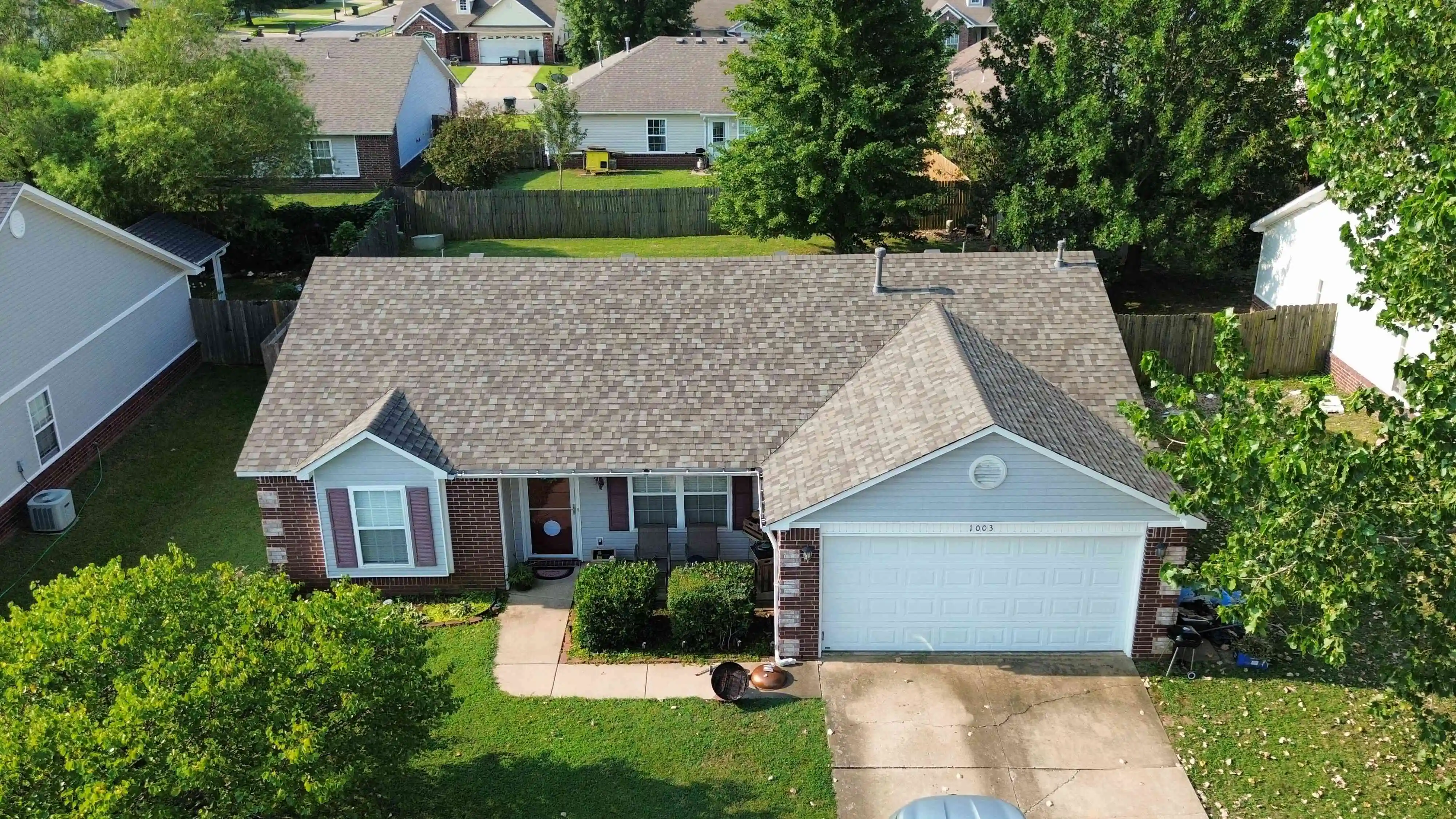 Aerial drone perspective showcases a complete residential roof replacement by Aces Roofing and Exterior Solutions located at 23rd Street and Chambers in Claremore, OK (36.331014, -95.620189). This project, captured at an altitude of 128.89 meters, showcases high-wind resistant asphalt shingles and professional ridge vent installation compliant with 2018 IRC standards.