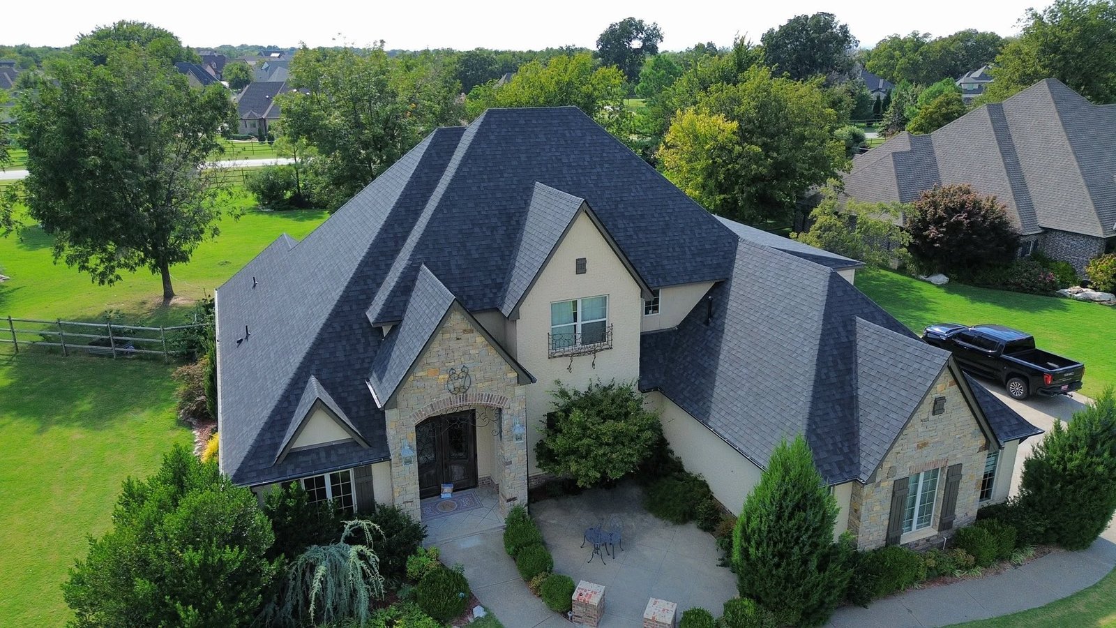 Aerial view of completed Owens Corning Duration Onyx Black roof on Stone Canyon, OK home showing multiple hips, valleys, and gables