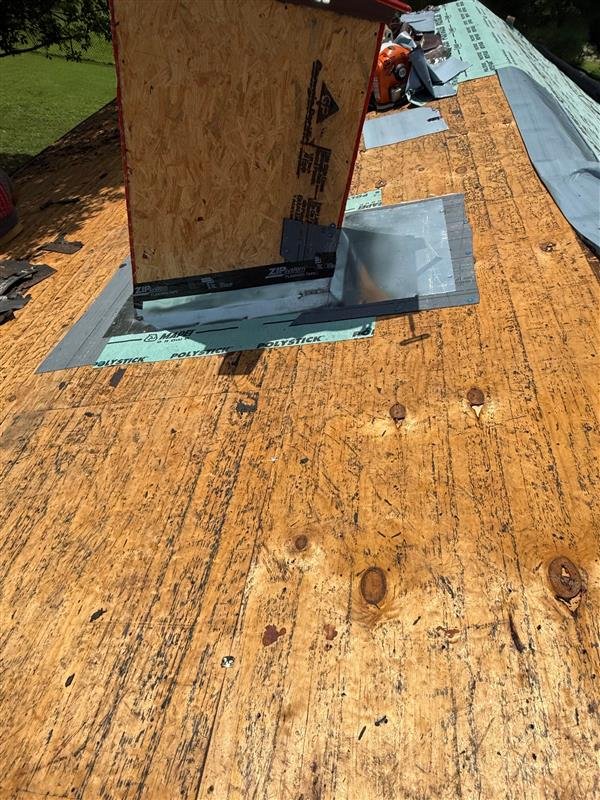 Metal flashing installed around the base of a brick chimney on a roof during roof leak repair