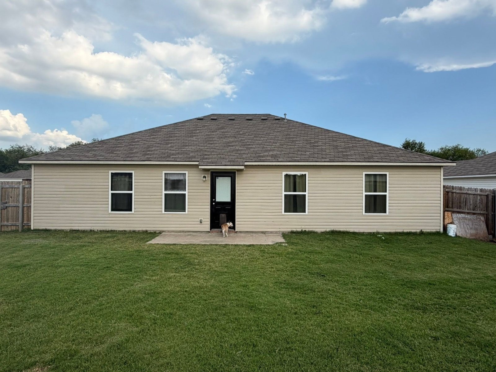 Rear elevation of Claremore, OK home after hail damage restoration, showing new Class 3 impact-resistant roof and replaced siding