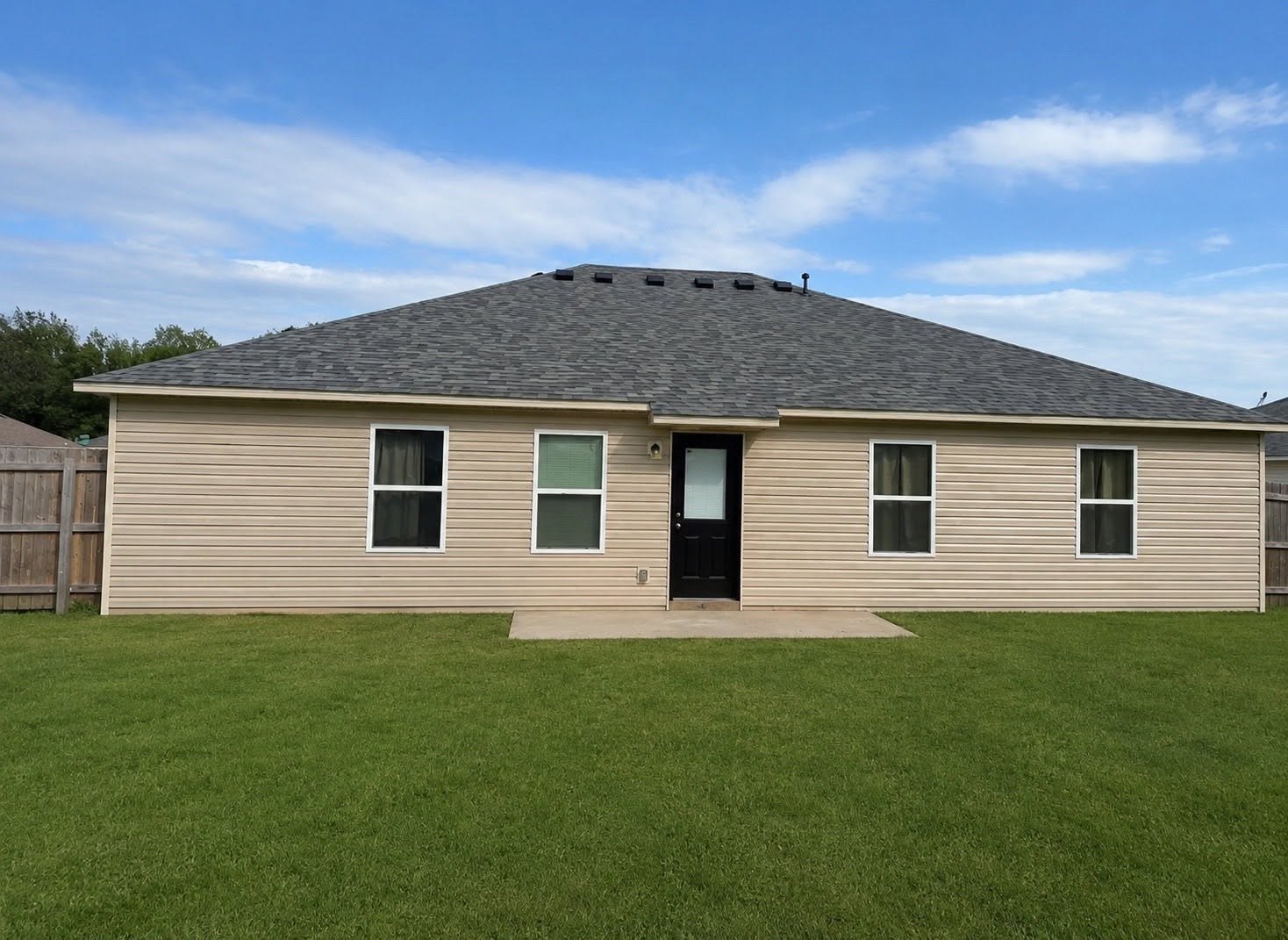 Rear elevation of Claremore, OK home showing completed roof, siding, and window restoration after hail damage