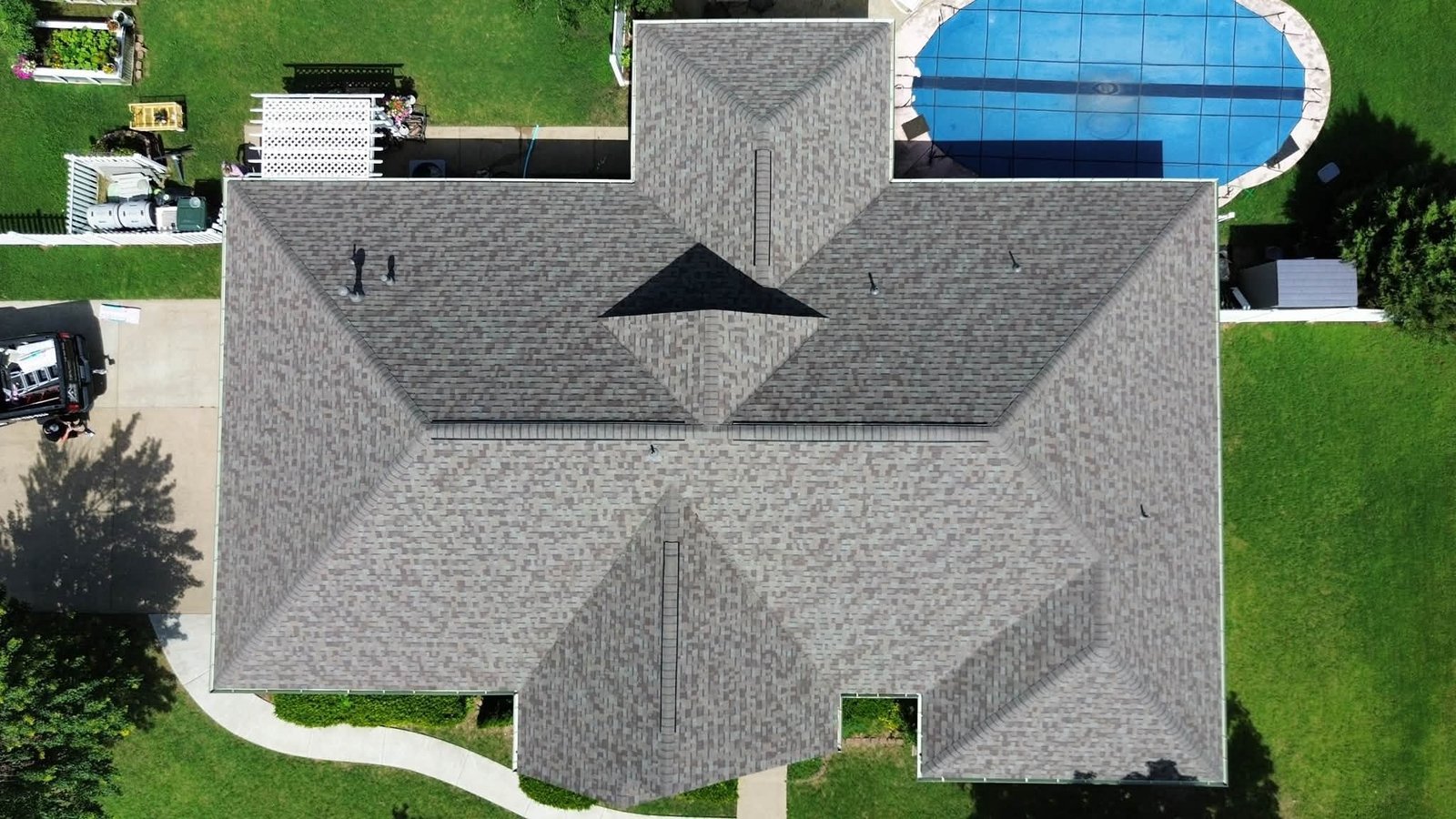 Aerial view of completed roof restoration in Claremore, OK featuring a Class 4 Owens Corning Duration FLEX roof on a home with an in-ground pool and multiple hip roof sections.