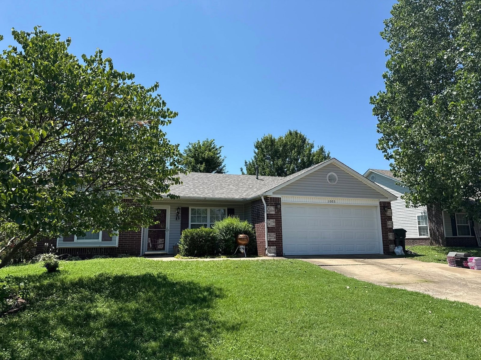 Ranch-style home in Claremore, OK on roof replacement day with Owens Corning shingle bundles staged on the driveway