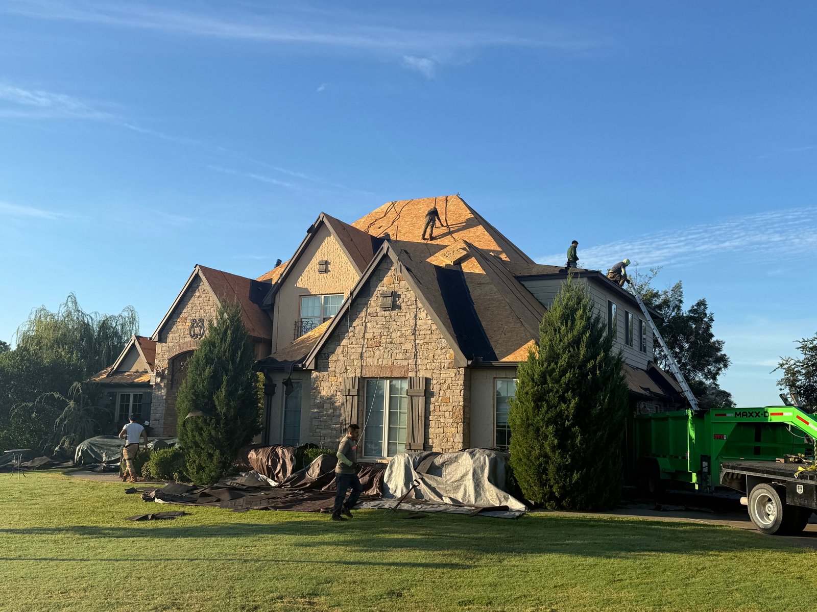 Hail damage roof replacement in Claremore, Oklahoma, showing shingle removal and exposed roof decking during storm damage repair