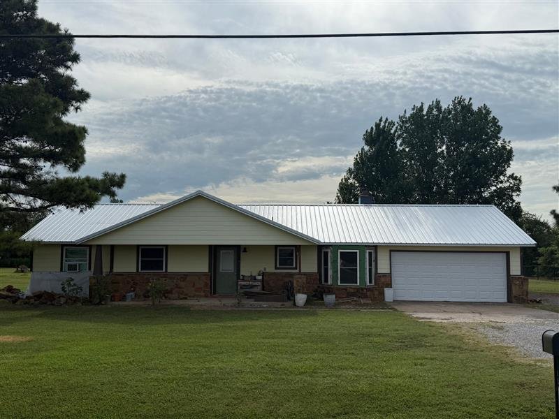 Residential home with a light-colored metal roof representing metal roof repair services by Aces Roofing and Exterior Solutions