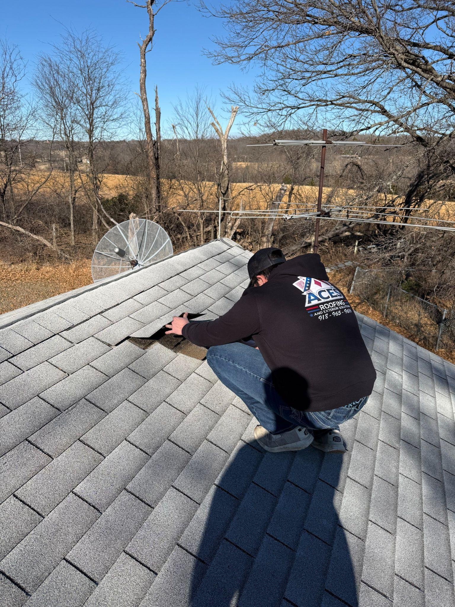 A roofing contractor from Aces Roofing and Exterior Solutions inspects asphalt shingles during a roof inspection in Claremore, Oklahoma